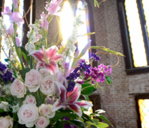 A flower arrangement lit by large windows.